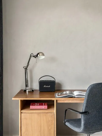 A close-up of the desk area in the son's room from the Warm Minimal home. The concrete-textured walls and simple wood desk create a clean, modern, and focused workspace.