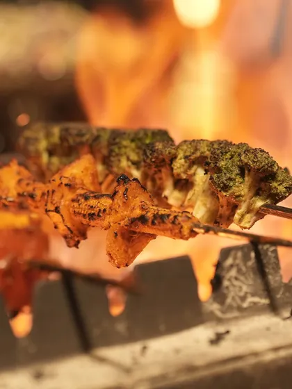 A closer look at our vegetable and paneer skewers being grilled to perfection. The open flame sears the outside while keeping the inside tender and juicy, creating an irresistible appetiser for guests.