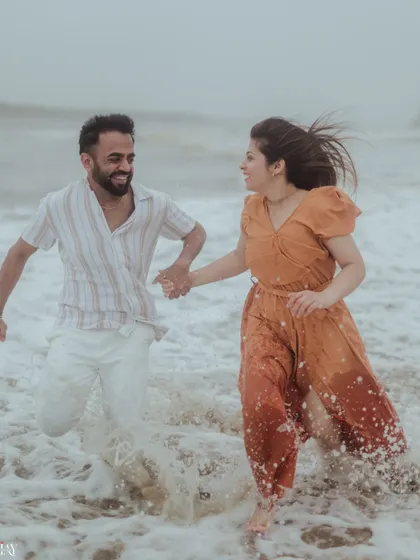 A candid shot of the couple running and laughing through the water, showcasing their playful connection.