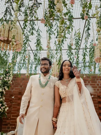 A modern and chic engagement ceremony with a white and green color palette. The couple stands under a ceiling of hanging greenery and floral chandeliers, creating a fresh and romantic atmosphere.