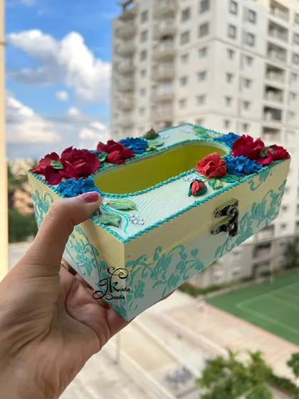 A side view of the red and blue tissue box, showing the textured filigree work on the sides.