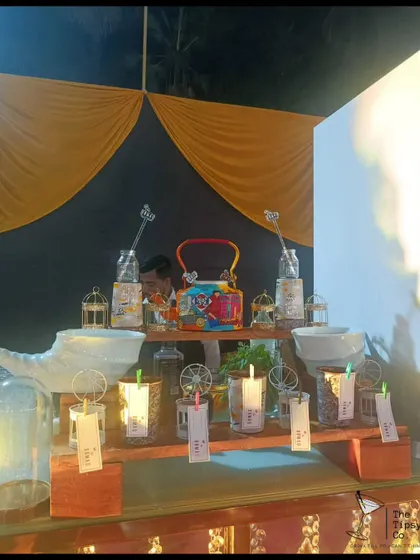 A quirky and rustic bar setup featuring a hand-painted kettle and birdcage decorations. The personalized tags and unique glassware show our creative approach to bar styling.