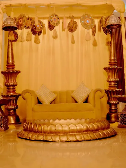 The seating arrangement for the groom's Haldi ceremony. I used a beautiful lotus-base sofa and traditional brass pillars against a simple yellow drape to create a classic and regal look.