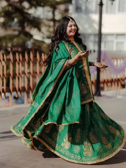 A full-length shot of the bride twirling in her green Mehandi outfit. The movement and her happy smile perfectly capture the celebratory mood of the function.