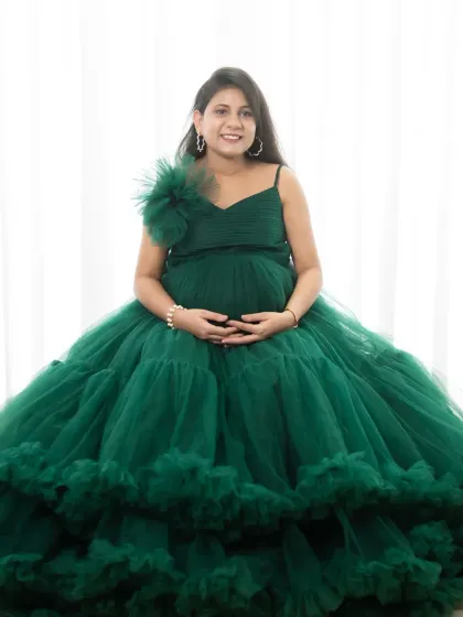 A full-length shot showcasing one of our beautiful green tulle gowns. The mom-to-be looks absolutely radiant in this high-key studio shot.