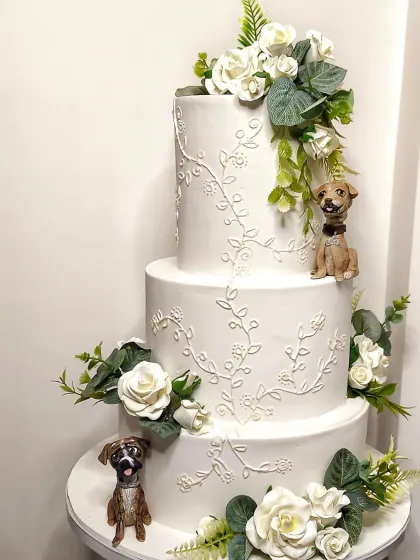 A wedding cake is personal, and nothing is more personal than including your fur babies. This elegant three-tier cake features delicate royal icing and sugar flowers, but the real stars are the custom, hand-sculpted figurines of the couple's beloved dogs, making their day even more special.