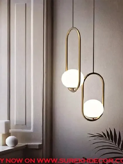These lustrous insignia hanging lights feature a milky white globe suspended within an elegant antique brass loop. They are perfect for hanging in pairs or clusters to create a sophisticated and modern lighting statement.