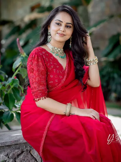 A close-up of the client in her red organza saree, highlighting her beautiful smile and the intricate jewelry.