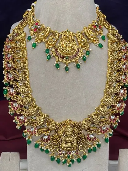 Here you can see the fine details of one of my antique bridal sets. This rental piece features Goddess Lakshmi motifs, peacock designs, and is studded with Kempu stones and green beads, available for your wedding in Bangalore.