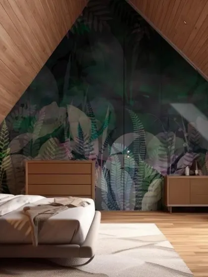 A dark, moody tropical wallpaper on an angled attic wall creates a dramatic and cozy bedroom sanctuary.