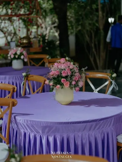 Pastel purple table linens with simple pink rose centerpieces for a Sangeet.
