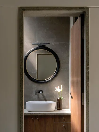 We used ocean green granite in various finishes for the bathrooms. This powder room features a vessel sink, a custom round mirror, and a dramatic beam of light from a skylight.