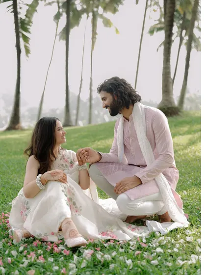 A peaceful pre-wedding scene in Goa, where the couple shares a quiet moment on a lush green lawn surrounded by tall palm trees.