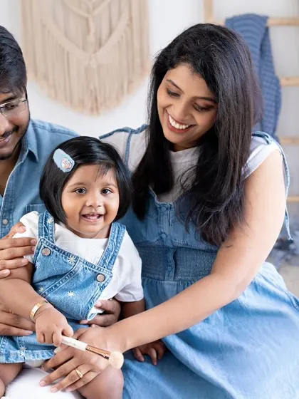 A family of three in matching denim, sharing a happy moment. The daughter's bright smile is the focal point of this cheerful and coordinated family portrait.