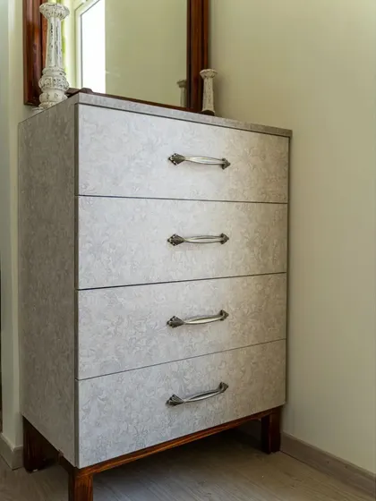 A custom chest of drawers with a textured laminate finish and classic metal handles, providing stylish storage in the guest room.