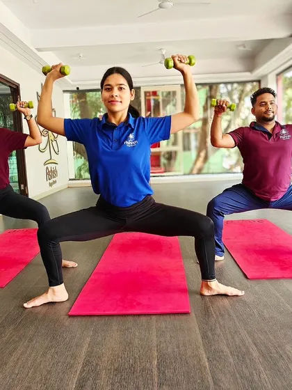 Students hold a powerful Goddess Pose with light weights, adding a strength training component to their yoga practice.