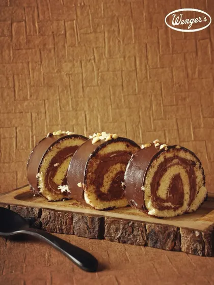 Our Chocolate Swiss Roll, sliced to show the perfect swirl of sponge and cream. Coated in chocolate and topped with nuts, it's a rich and satisfying dessert.