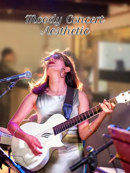 I'm looking upwards while playing guitar, with the microphone beside my face and warm lights behind this live music set.