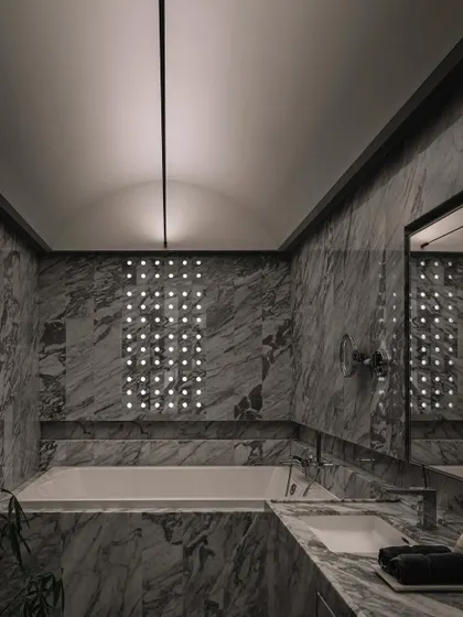 The master bathroom, where a vaulted ceiling is illuminated by a tensioned rope light, highlighting the curves above the bathtub.