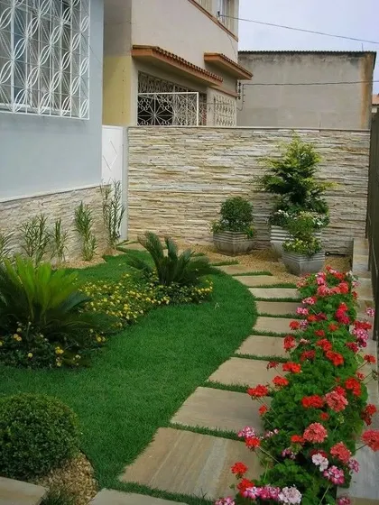 A side yard garden featuring a winding stone path through a small lawn. We used a combination of flowering plants, shrubs, and a stone-clad wall to create a charming and colorful walkway.