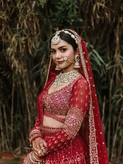 A stunning portrait of the bride in her vibrant red wedding lehenga. Her confident pose and the rich colors make this a powerful and beautiful bridal shot.
