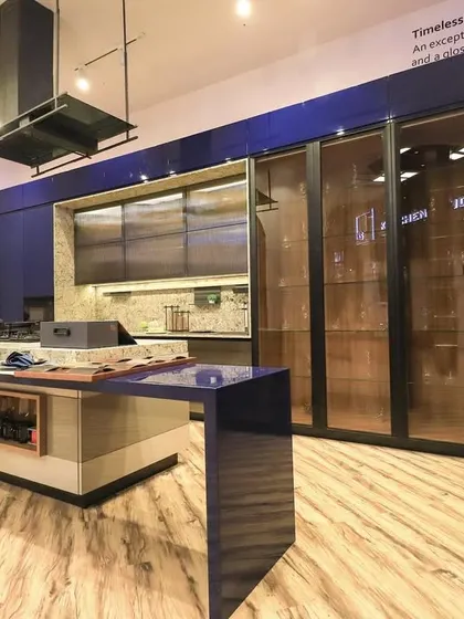 Another angle of the blue and wood kitchen, showing the island with an integrated hob and a small breakfast counter. This design is perfect for those who love to cook and entertain.