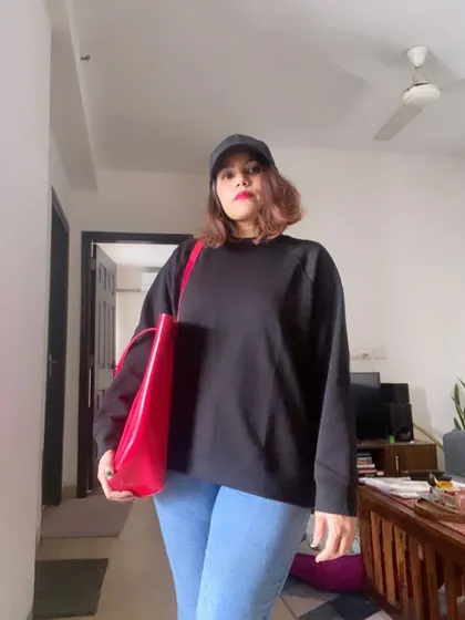 My official welcome to winter. A cozy black sweatshirt, comfortable jeans, and a baseball cap are my essentials. I add a pop of color with a bright red tote bag to liven up a gray day.