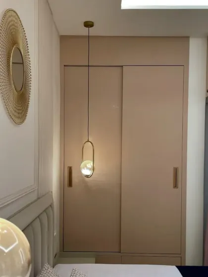 A close-up of the bedroom's details, including the elegant pendant lighting and the smooth, handleless sliding wardrobe. We use high-quality PU and Laminate finishes for a distinctive look.