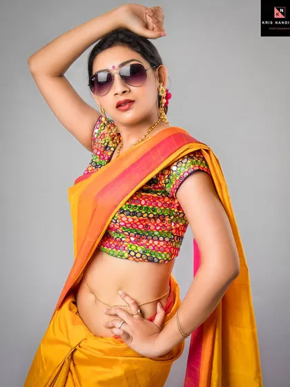 A playful and modern take on the 'sanskari' look. The model wears a bright yellow saree with a colorful blouse and sunglasses, striking a pose full of attitude and swag.