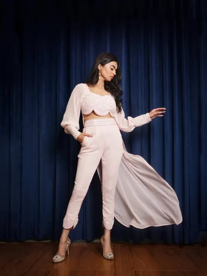 A graceful pose showing the full length of the trousers and the dramatic sweep of the cape. This is a perfect final shot for a designer series.