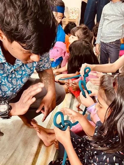 An outdoor educator teaches the children how to tie essential knots. Learning practical, real-world skills like this builds confidence and a sense of capability.