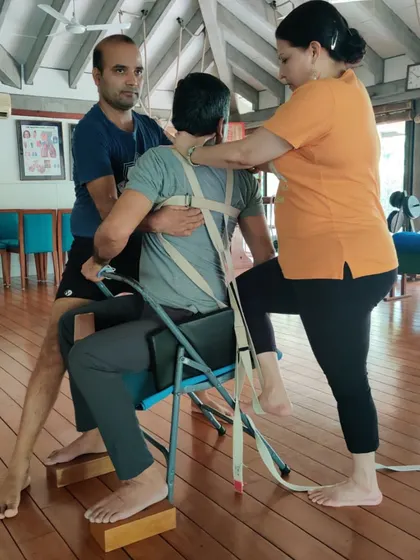 This is a complex, team-assisted adjustment in a seated pose. It shows the level of care and precision we take to help students overcome their limitations and find new possibilities in their bodies.
