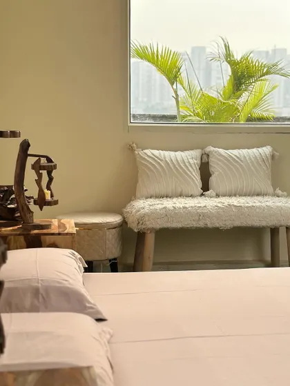 A peek into the cozy indoor studio. This corner features a boho-style bench and a window with a view of the green patio, blending the indoor and outdoor spaces.