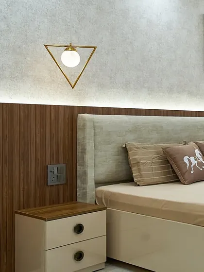 A close-up of the bedside in this neutral-toned bedroom. The horse-themed cushions add a personal touch, and the triangular pendant light is a modern design element.