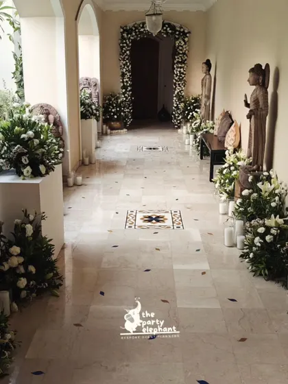 The same elegant hallway captured in natural daylight, showcasing the beauty and freshness of the white floral arrangements before the evening's candlelit event began.