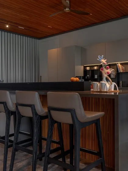 This kitchen in Ahmedabad, designed by DK Design Lab, is defined by architectural clarity. The layered island combines wood shelving with dark counters, creating a functional and visually interesting centerpiece.