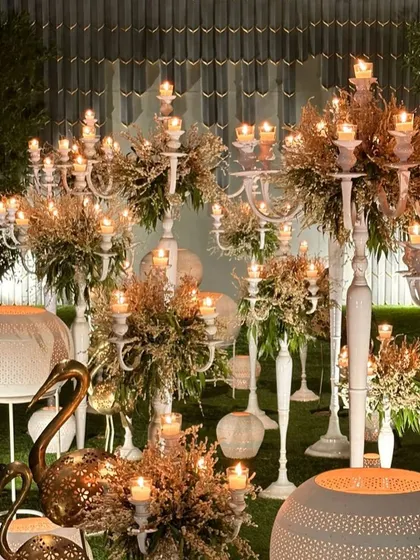 A detailed shot of the white and gold decor corner, showing the texture of the dried flowers and the warm candlelight.