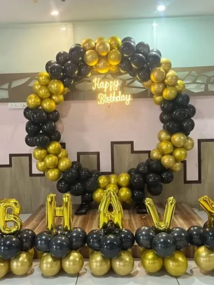 A fun Boss Baby theme for Bhav's birthday. The setup includes a circular balloon arch in black and gold, character cutouts, and foil balloons spelling out the name.