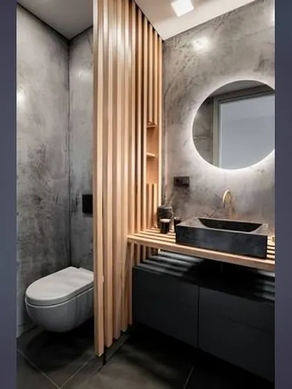A minimalist bathroom with a wooden slat partition separating the toilet area. The black vessel sink and dark floor create a striking contrast with the light wood.