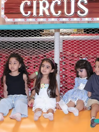 A group of children sitting together in front of the "Circus" sign in our play area.