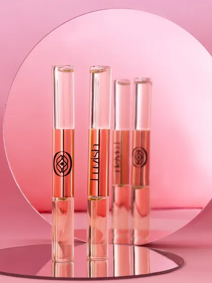 This shot uses mirrors to create a repeating reflection of the perfume rollers. The monochromatic pink theme and reflections give it a sophisticated, glamorous, and slightly abstract feel.