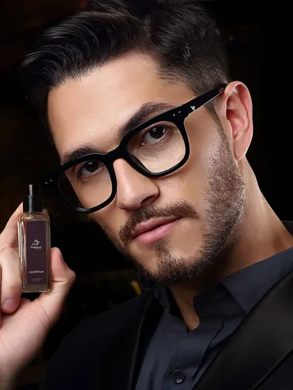 A sophisticated close-up of a male model holding a small perfume bottle, conveying a sense of luxury and intimacy.