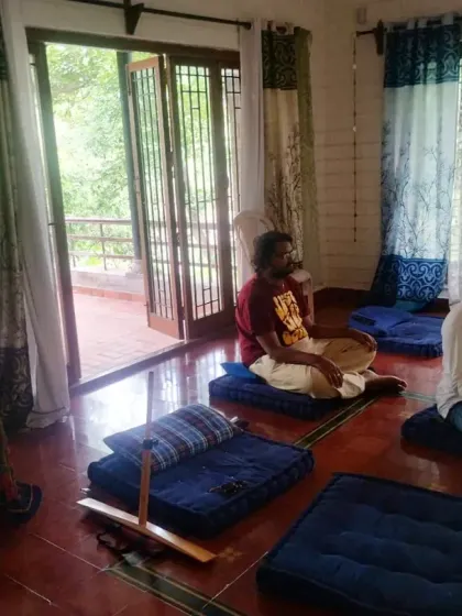 A group meditation at our retreat center, where individuals sit on cushions with a peaceful and focused demeanor. The natural light and tranquil surroundings provide the perfect setting for deep introspection and communion with the Divine.