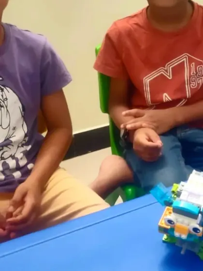 Two students with their completed robotic project, ready to test the code they've written for it.