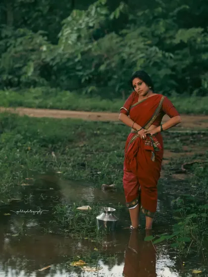 A rustic, village-themed series inspired by the movie 'Kanthara'. The model is styled in a simple red saree, captured in a natural, watery landscape to evoke a sense of raw, earthy beauty.