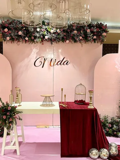 A full view of Nida's pretty-in-pink birthday party. The setup included a large custom backdrop, oversized paper flowers, and elegant floral arrangements in shades of pink and burgundy.