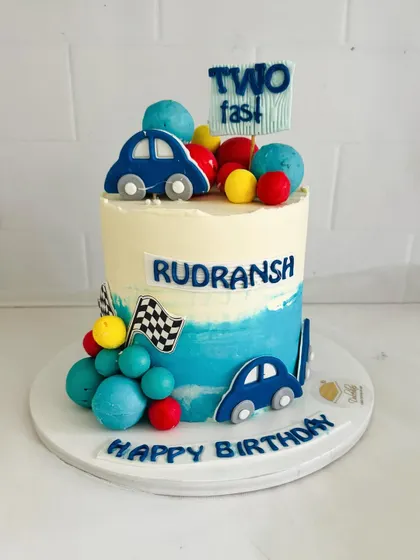 A full view of the adorable "Two Fast" birthday cake with its blue ombre effect and fondant cars.