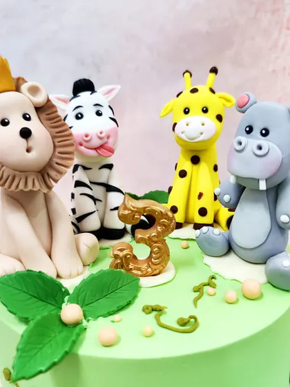 A detailed close-up of the handcrafted jungle animal toppers, showcasing their playful expressions and unique features.