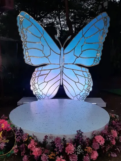 A giant butterfly photo booth that lights up at night, providing a magical and interactive element for guests to enjoy.