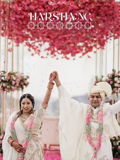 A moment of pure celebration after the varmala ceremony, with the couple framed by a stunning pink floral mandap.